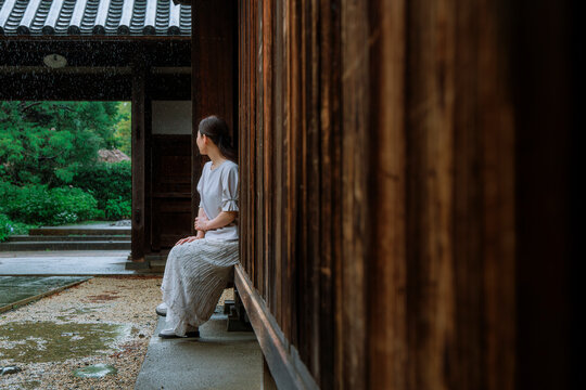 Woman Sheltering from Rain under a Traditional Japanese Engawa.