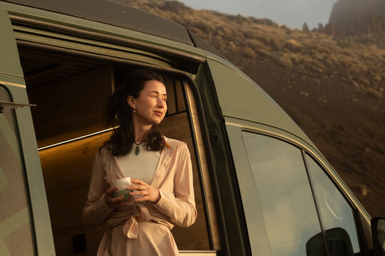 Woman enjoying a quiet sunrise beside her camper van
