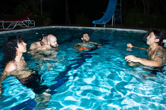 Friends Enjoying a Night Swim in a Pool Under the Stars