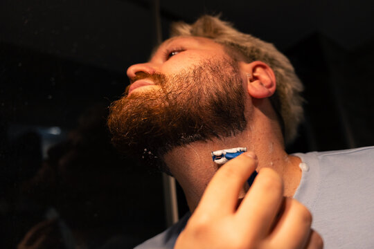 Low Angle View Of Man Shaving Beard Neckline