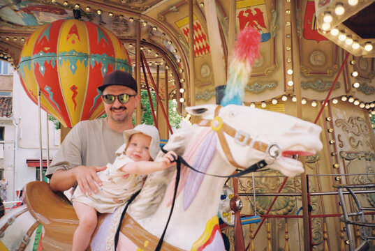Portrait of a father with daughter riding carousel horses