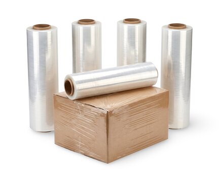 Stretch film rolls with unrolled plastic wrap beside cardboard box, isolated on white background