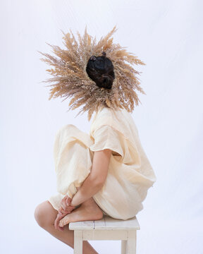 Woman Hiding Behind Dried Wreath in White Studio