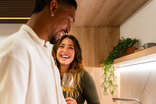 Happy couple laughing in modern kitchen with wine glass