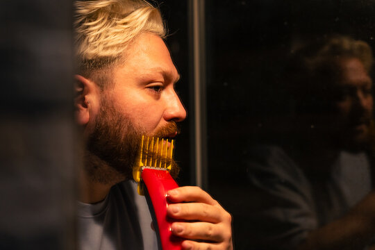 Man Trimming Beard While Looking Into Mirror