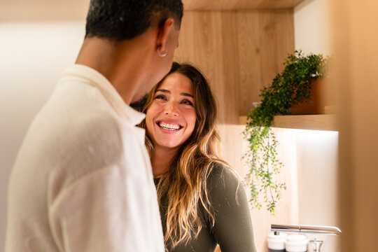 Happy multiethnic couple smiling in modern kitchen at home, candid