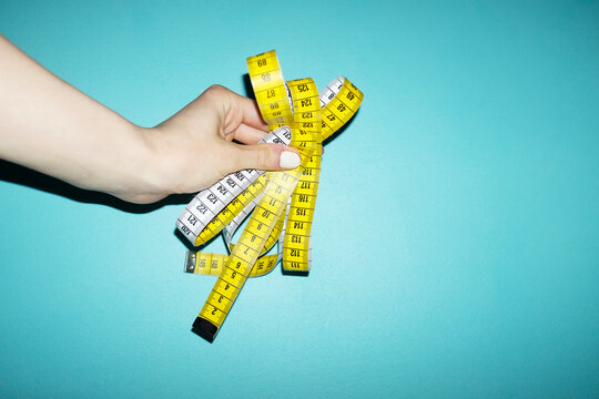 Hand holding yellow measure tape with metric and numbers with flashlig