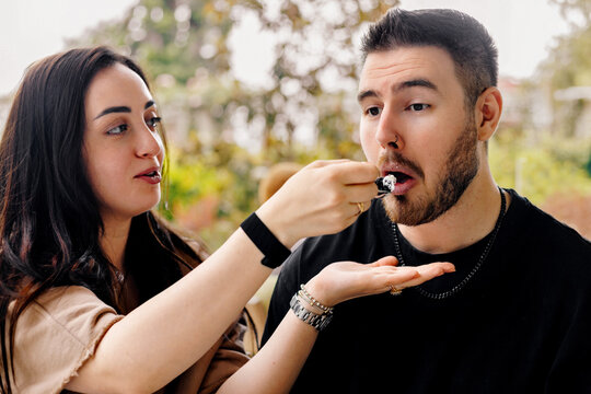 The girl is feeding her boyfriend cake