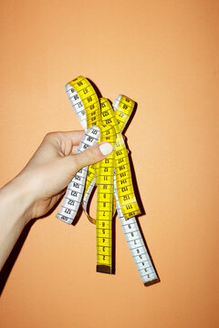 Hand holding yellow measure tape with metric and numbers with flashlig