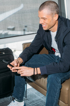 Smiling traveler using phone before flight