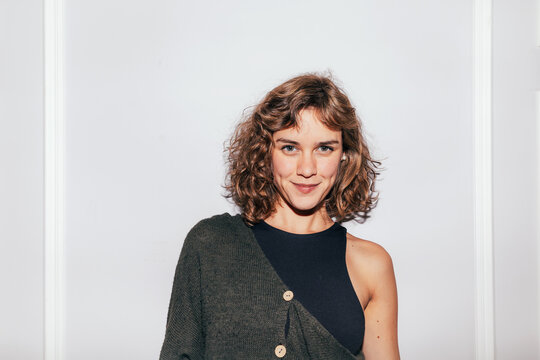 Smiling young woman with curly hair in studio portrait