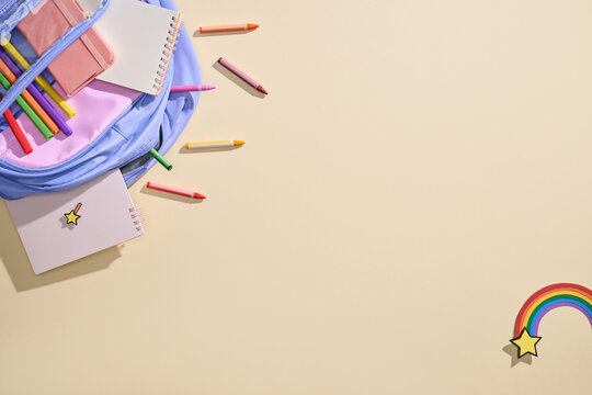 Back to school supplies spilling out of a backpack with crayons
