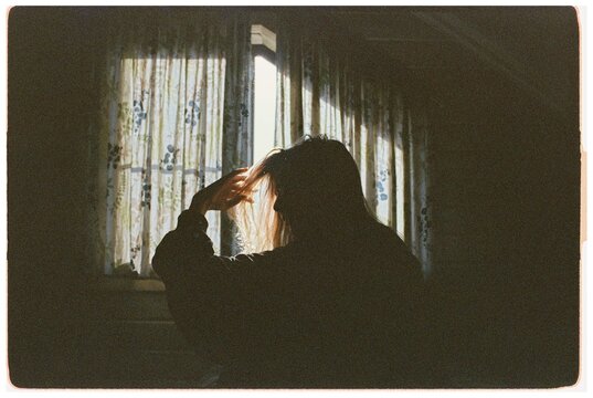A portrait of a girl against a window in a cloud of dust