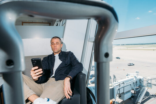 Man Waiting in Airport Looking at Phone