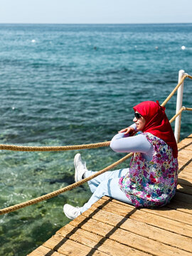 Woman Sitting on Pier with Ocean Backdrop