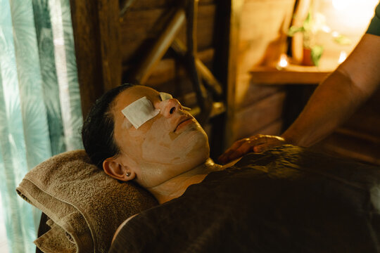 Client receiving a facial treatment and shoulder massage at a spa