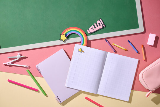 Back to school supplies arranged on a pink and yellow surface
