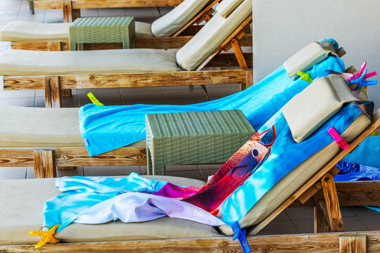 Close-up view of colorful towels secured with clothespins on sun loungers at hotel patio. Crete. Greece.
