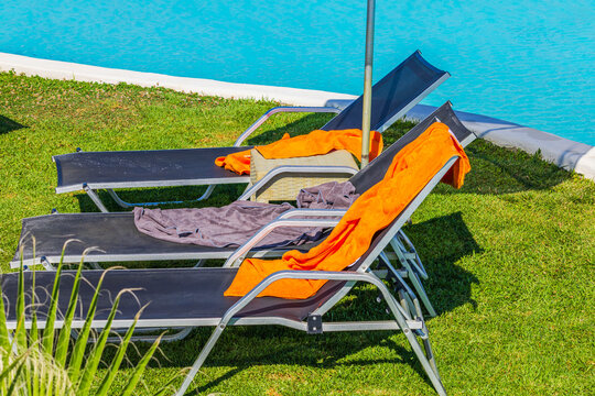 Close-up view of sun loungers with towels on green lawn beside hotel swimming pool. Crete. Greece.