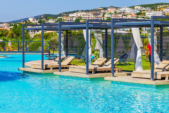 Beautiful view of hotel swimming pool with cabanas, sun loungers and hillside villas. Crete. Greece.