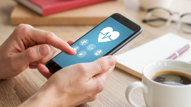 Close up photo of hands using mobile phone displaying health app application with medical interface on screen near coffee cup