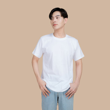 Young man in a plain white t-shirt and denim jeans posing against a neutral background