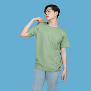 Young man in a green t-shirt and patterned pants posing against a blue background