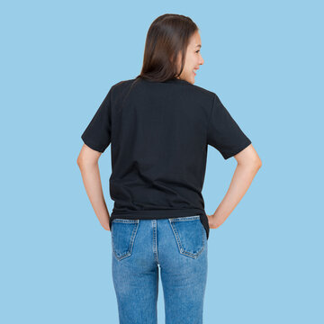 Young woman in black t-shirt and blue jeans standing with hands on hips