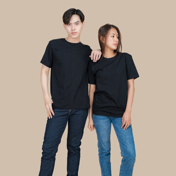 Young Asian couple in matching black t-shirts and denim jeans posing together