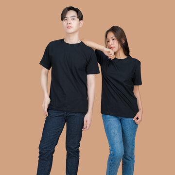 Young Asian couple in matching black t-shirts and jeans posing against a neutral background