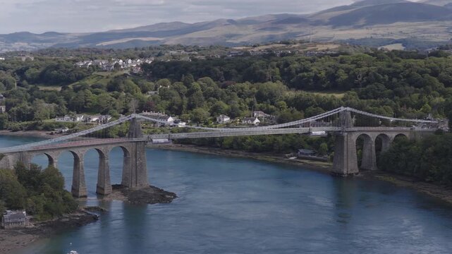 Establishing aerial view of the Menai Suspension Bridge which crosses the Menai Straits to connect the island of Anglesey and the mainland of Wales.