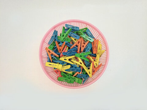 A basket full of clothes pins isolated on the white background, multi color plastic laundry clips or clothes pegs for house