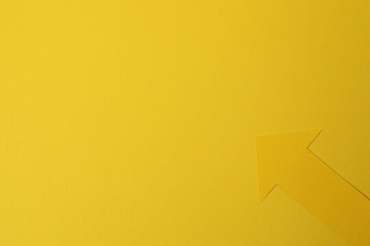 Paper arrow on color background, top view