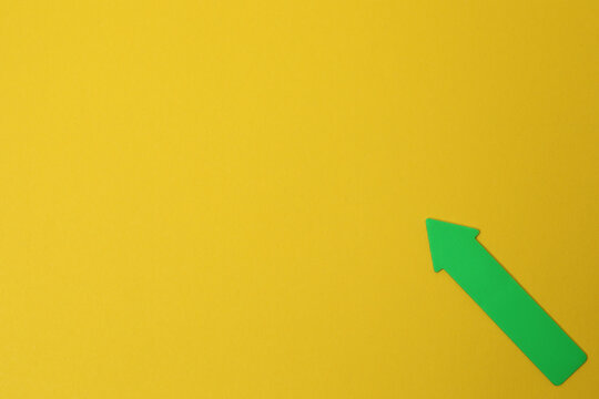 Paper arrow on color background, top view