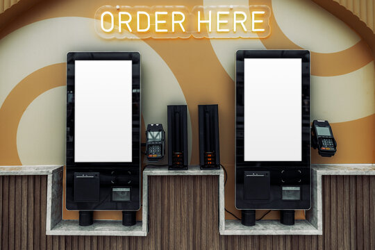 Two self-service restaurant terminals with blank vertical screens, card readers and receipt printers form a ready-to-customize digital menu and ordering interface mockup