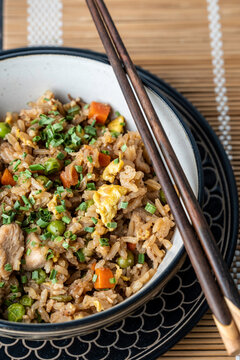 Chicken fried rice with chives in a ceramic bowl on a dark surface 