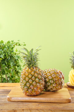 Fresh Whole Pineapples on Wooden Board with Green Background - Tropical Fruit Display