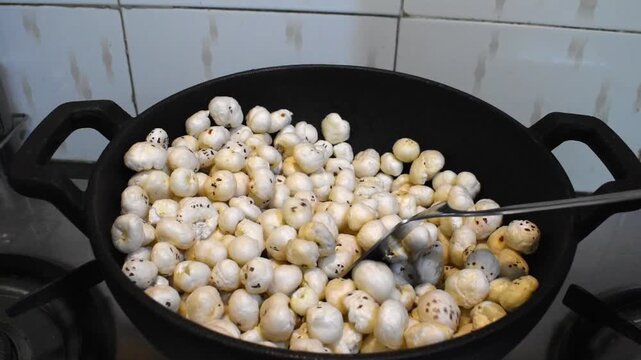 roasting makhana or foxnut in cast iron kadhai for making snacks or sweet