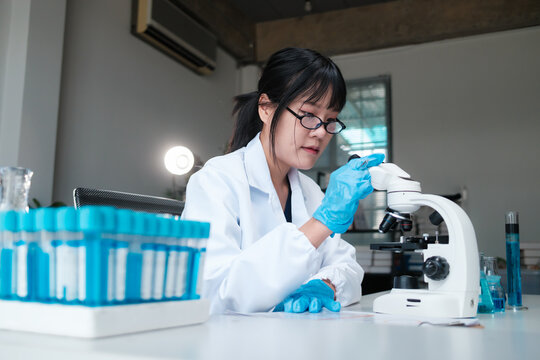 Young female scientist researching using microscope in laboratory