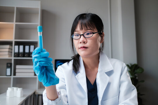 Asian scientist conducting experiment examining sample in laboratory