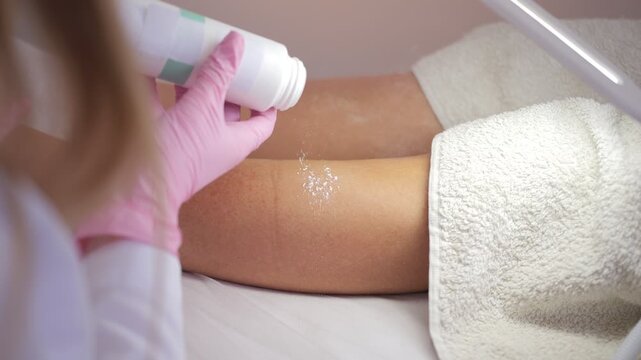 Esthetician applying talcum powder before hair removal treatment