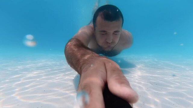 Man running toward a swimming pool on vacation, diving into the water and swimming underwater, dynamic underwater footage, clear blue pool water, cinematic 4K video, active lifestyle and summer sports