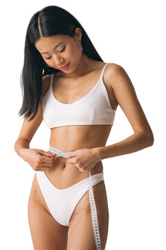 Asian female in white bikini measuring waist line with tape measure
