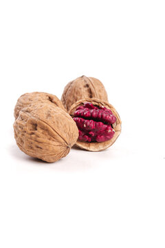 Red-skinned Xinjiang walnuts with cracked shell showing red kernel meat on white background