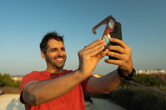 Man photographing solar eclipse with smartphone and solar filter