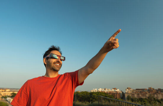 Man wearing solar eclipse glasses pointing sky during observation