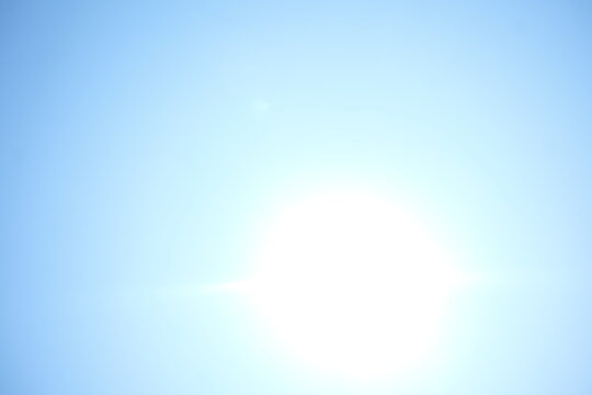 Bright sun flare in clear blue sky background copy space