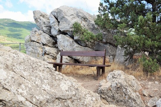 A summer mountain landscape. A wooden bench stands high in the mountains.