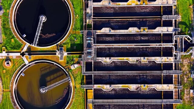 Aeration basin and circular tank. Long rectangular channel with metal walkway sits beside round clarifier in a wastewater facility.