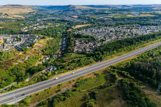 A465 Heads of the Valleys dual carriageway running past residential housing and green hillsides, Ebbw Vale, South Wales, aerial high angle view